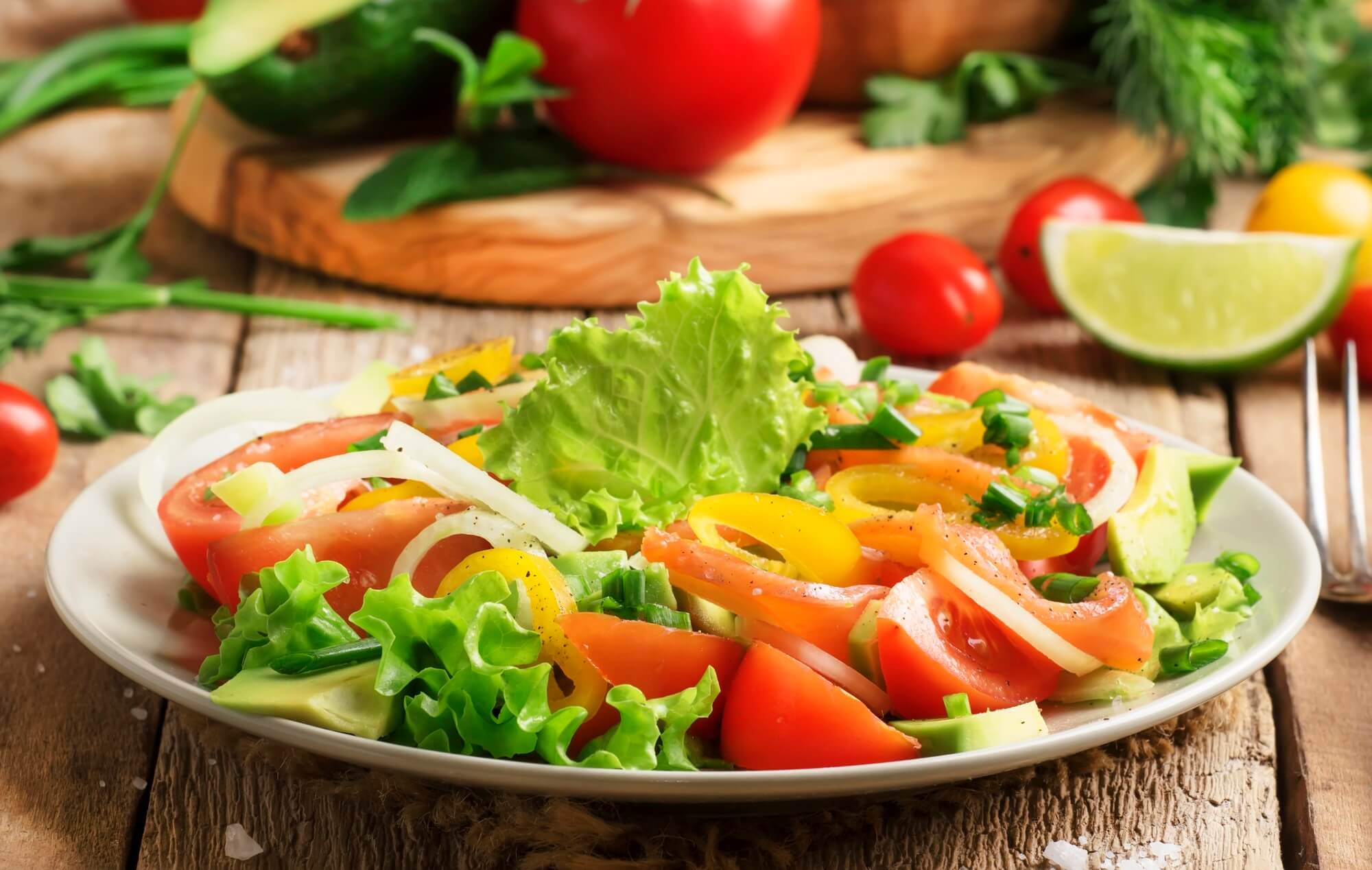 Salad with vegetables, avocado, shrimp and trout, source of omega-3, served in plate, wood kitchen table, selective focus